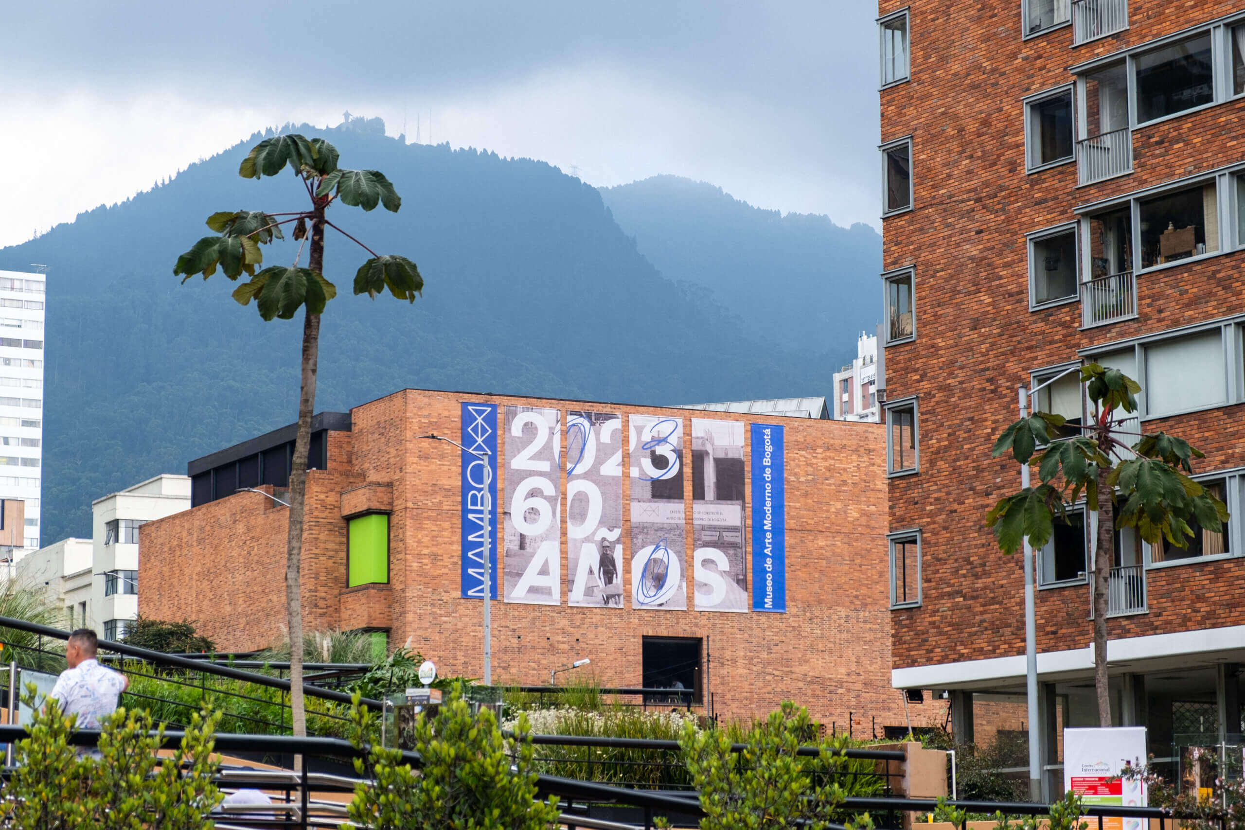 Tres hombres desnudos adoptando posturas geométricas frente a una ventana durante la exposición "Postura y Geometría en la Era de la Autocracia Tropical" de Alexander Apóstol en el Museo de Arte Moderno de Bogotá. La exposición se lleva a cabo del 14 de marzo al 9 de junio de 2024.